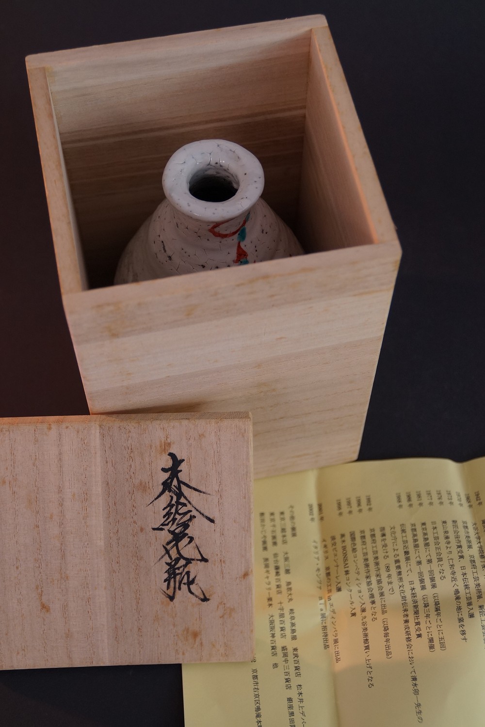 Die Sake Flasche stehend in der geoeffneten Aufbewahrungsbox mit Auszeichnungsurkunde