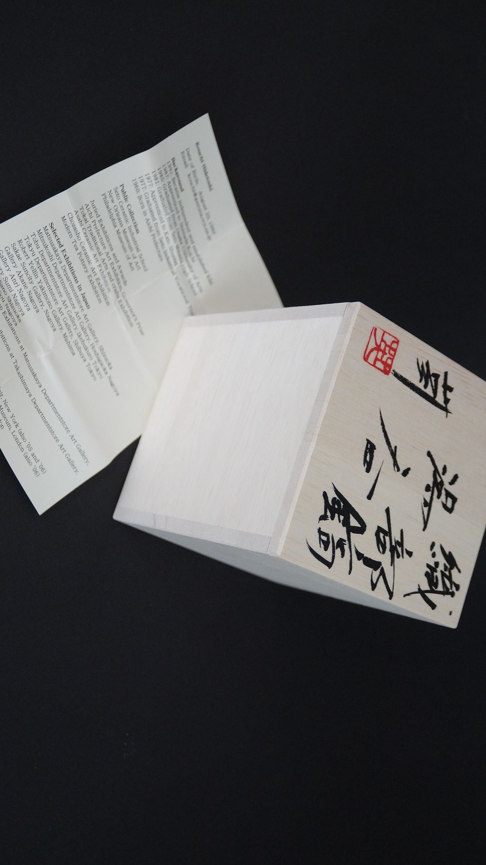 Signierter Kastendeckel mit rotem Kuenstlersiegel neben der Kuenstlerbiografie der Yunomi Tee-Schale aus Oribe-Keramik