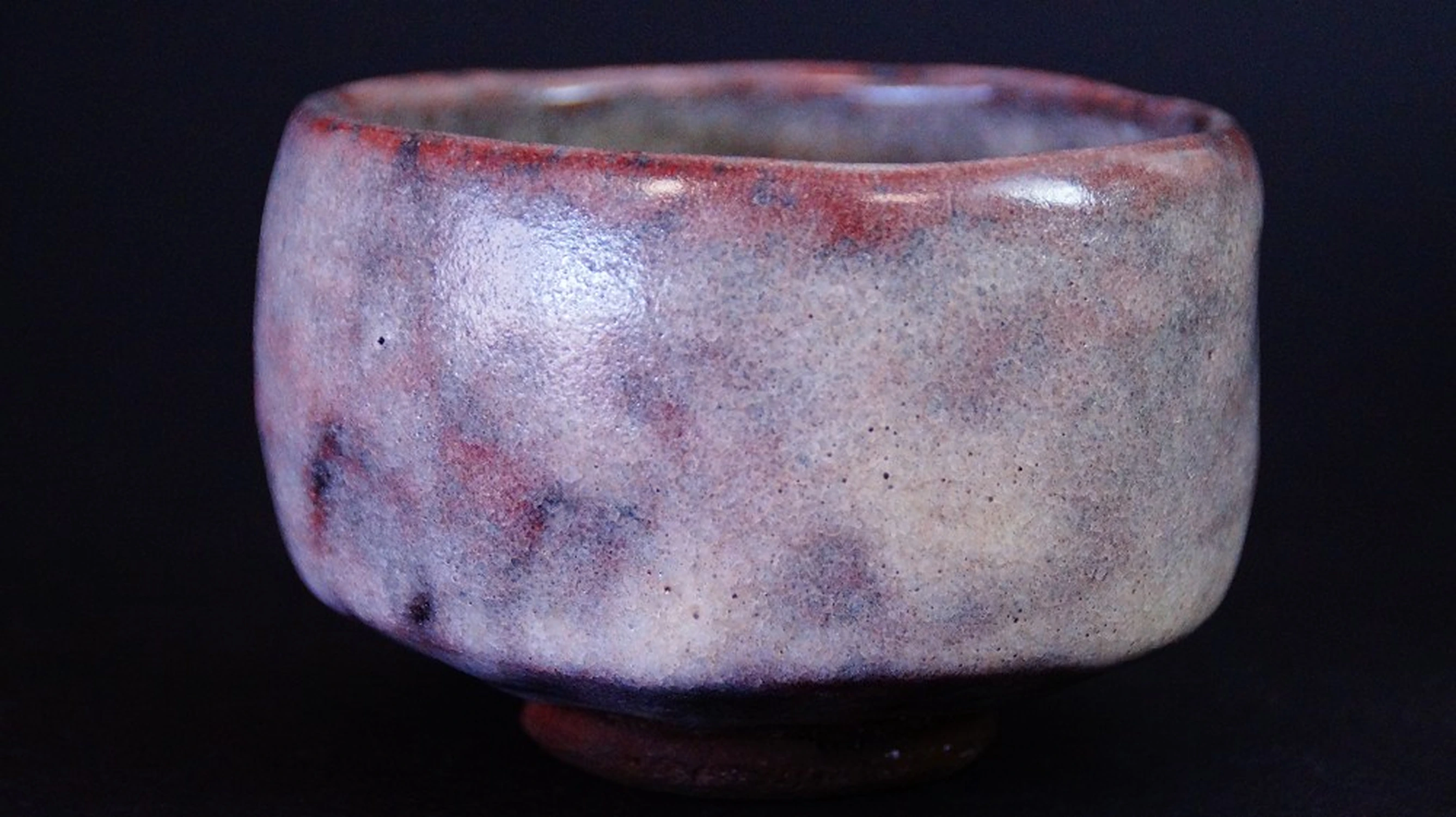 Vista lateral del chawan de cerámica de Ohi con esmalte tornasolado rojizo-marrón de Kaihatsu Bunmei