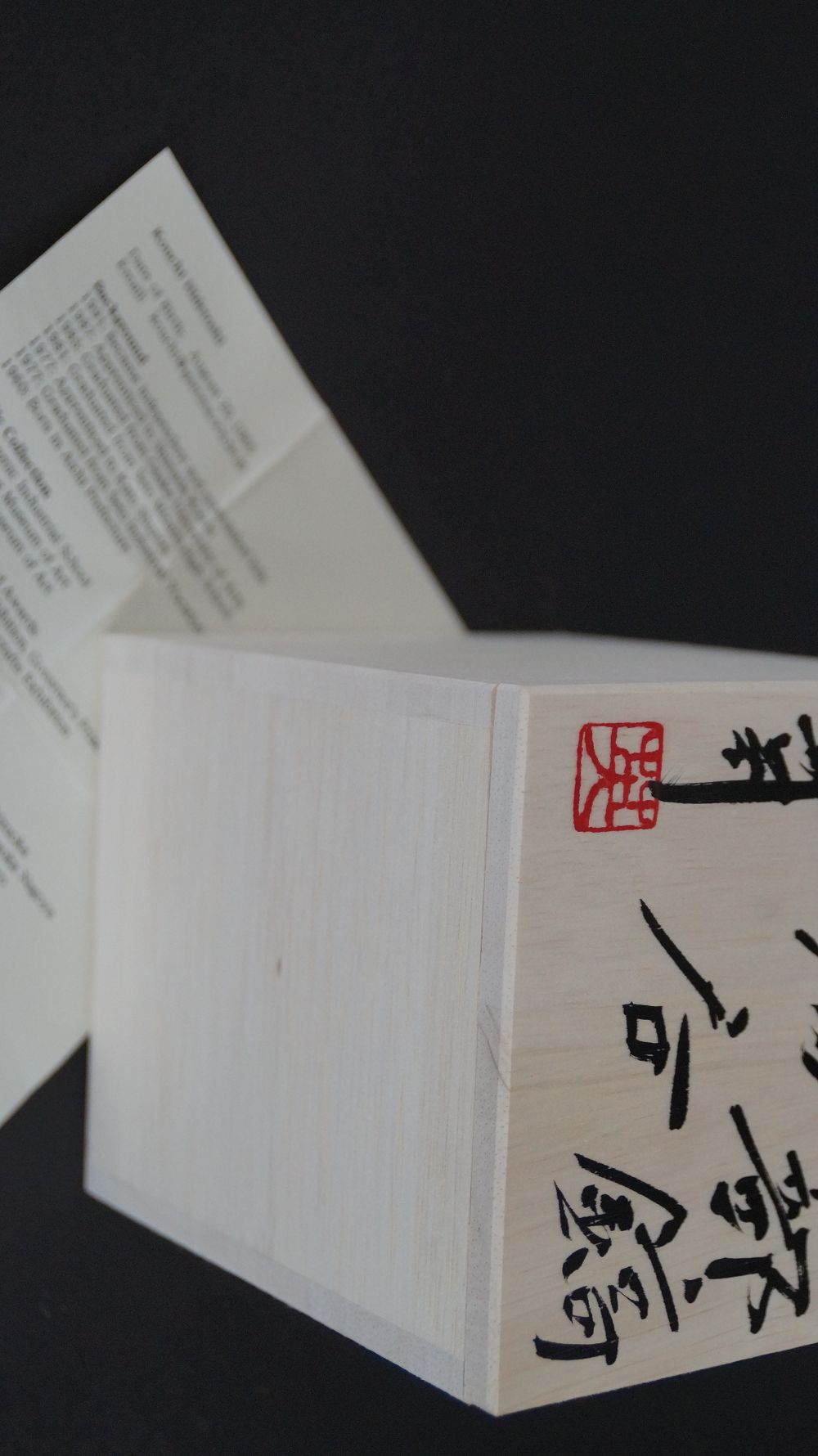 Signierter Kastendeckel mit rotem Kuenstlersiegel neben der Kuenstlerbiografie der Yunomi Tee-Schale aus Oribe-Keramik