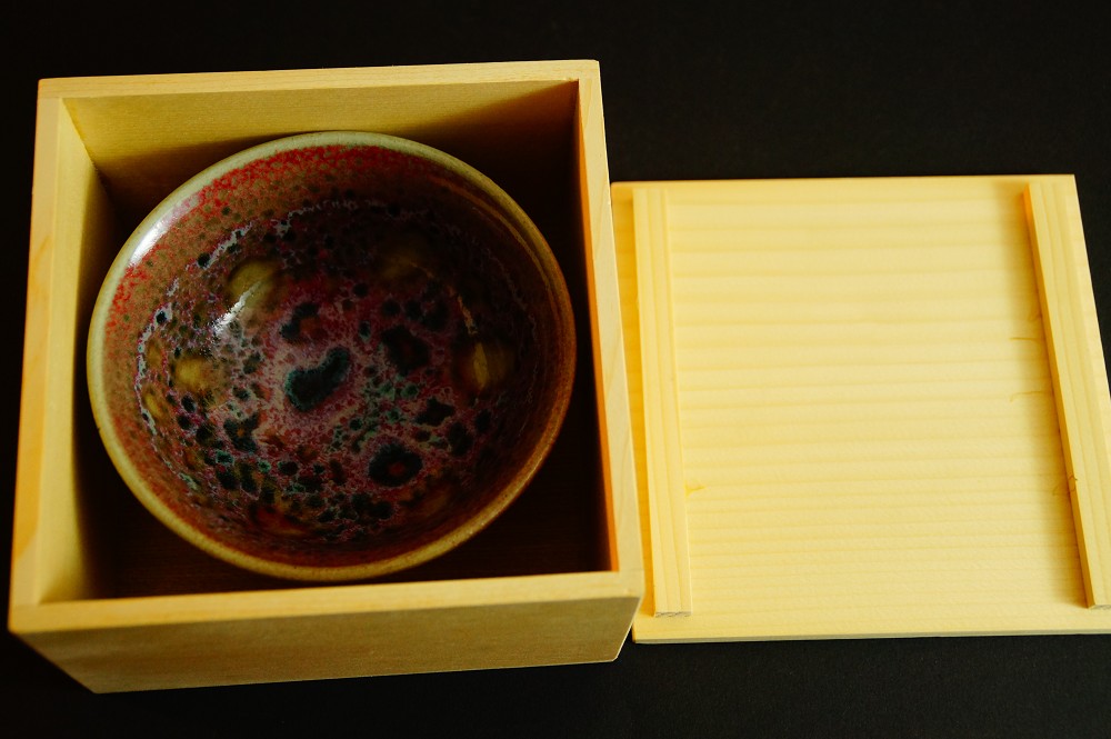 Chawan aus Kobushi-Keramik in der geoeffneten Aufbewahrungsbox neben dem Deckel