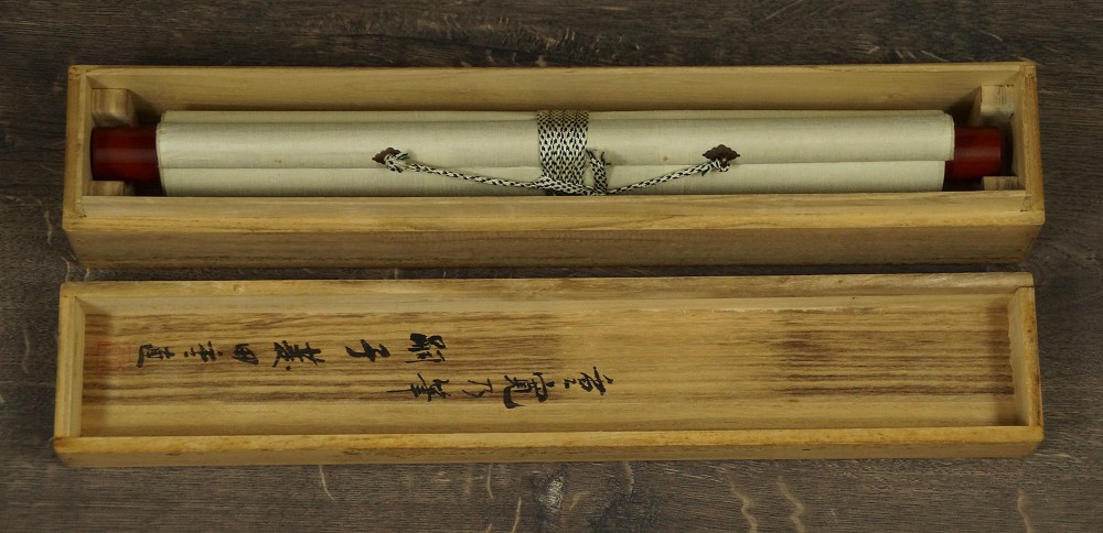 El kakemono enrollado y atado con cordón, colocado en la caja de conservación abierta