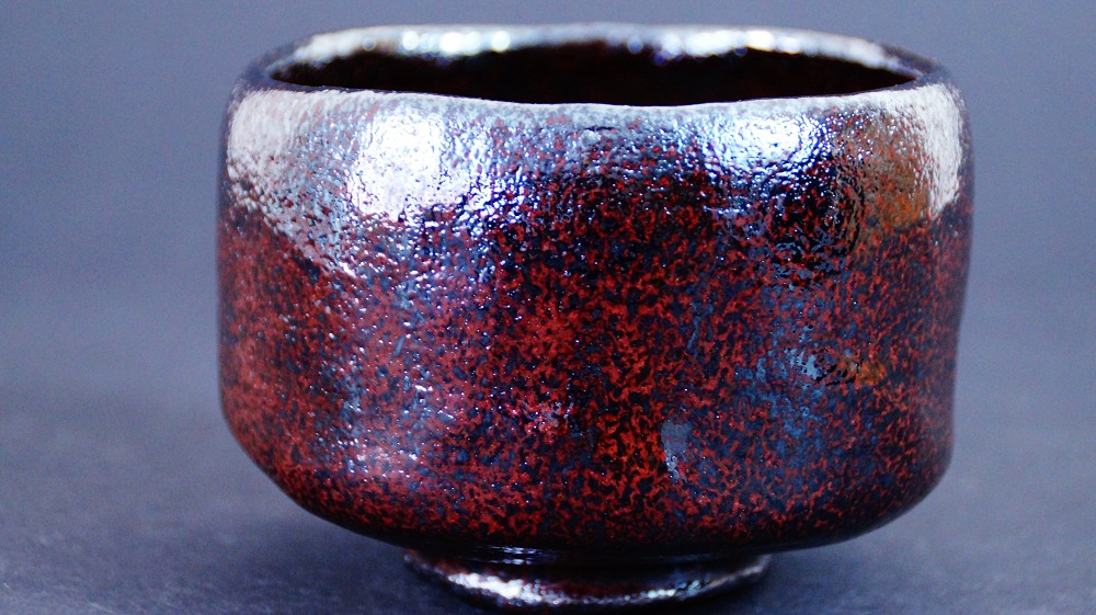 Seitenansicht der Chawan aus Raku-Keramik von Shoraku Sasaki mit unregelmaessiger Wandung und rotbraun-schwarz melierter Glasur