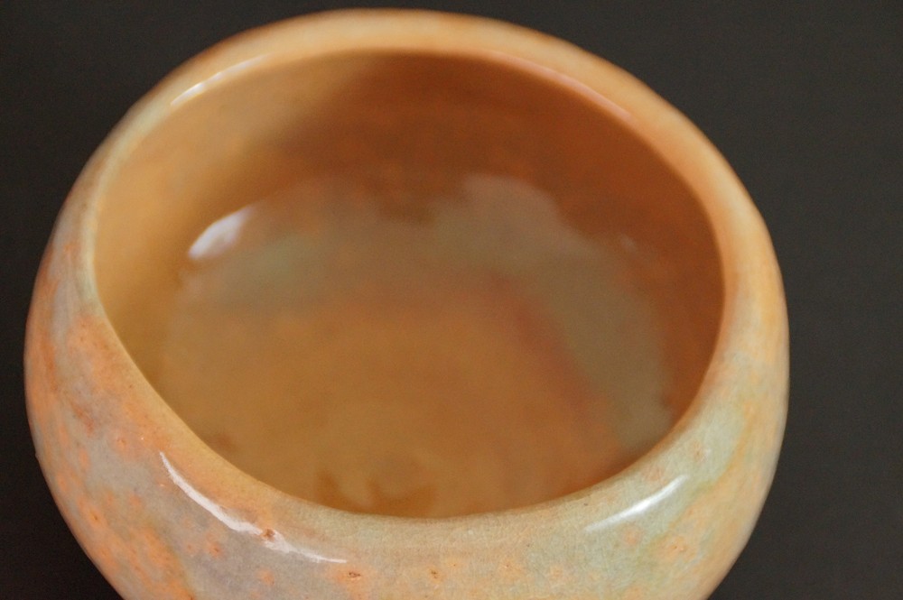 Primo piano dello smalto dai riflessi caldi bruno-arancio all'interno del chawan