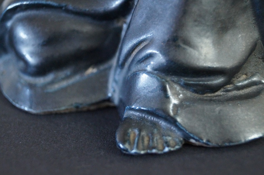 Figura de Bodhidharma Daruma de porcelana negra primer plano del pie