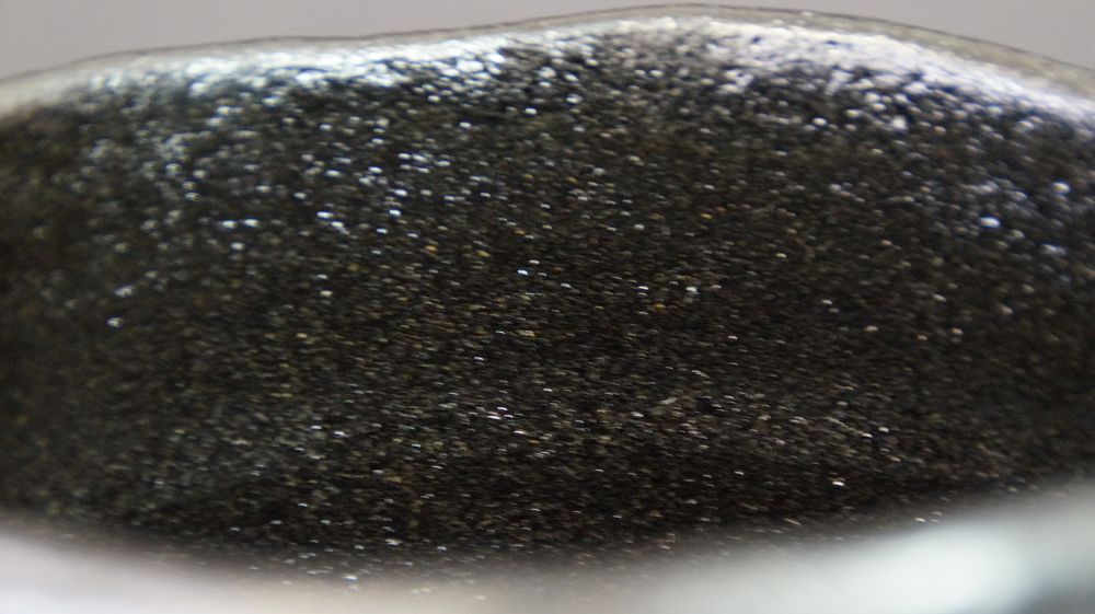 Primer plano del borde con esmalte negro finamente moteado del chawan de cerámica Raku
