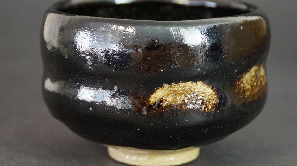 Autre vue de la chawan en céramique Raku avec surface émaillée noire chatoyante