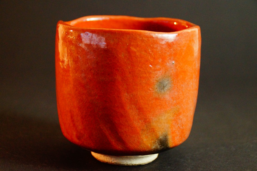 Seitenansicht des Chawan mit dunklen Brandspuren in der roten Glasur von Seiraku