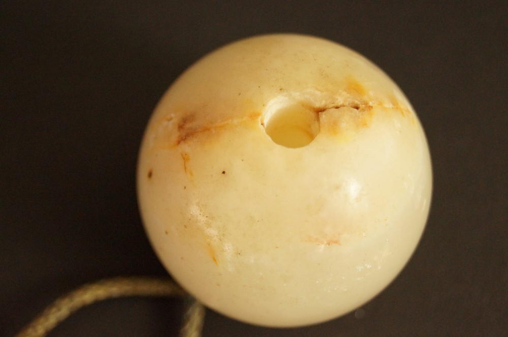 Sfera di pietra chiara con foro e macchie rossastre primo piano pietra 1