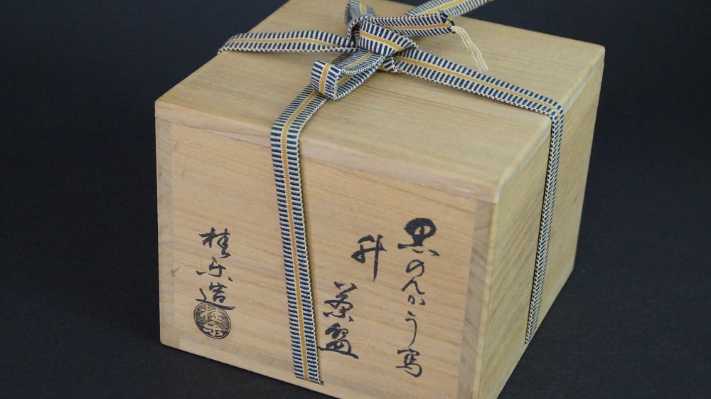 Geschlossene, mit gestreiftem Band verschnuerte Aufbewahrungsbox der Chawan aus Raku-Keramik mit Kuenstlersignatur
