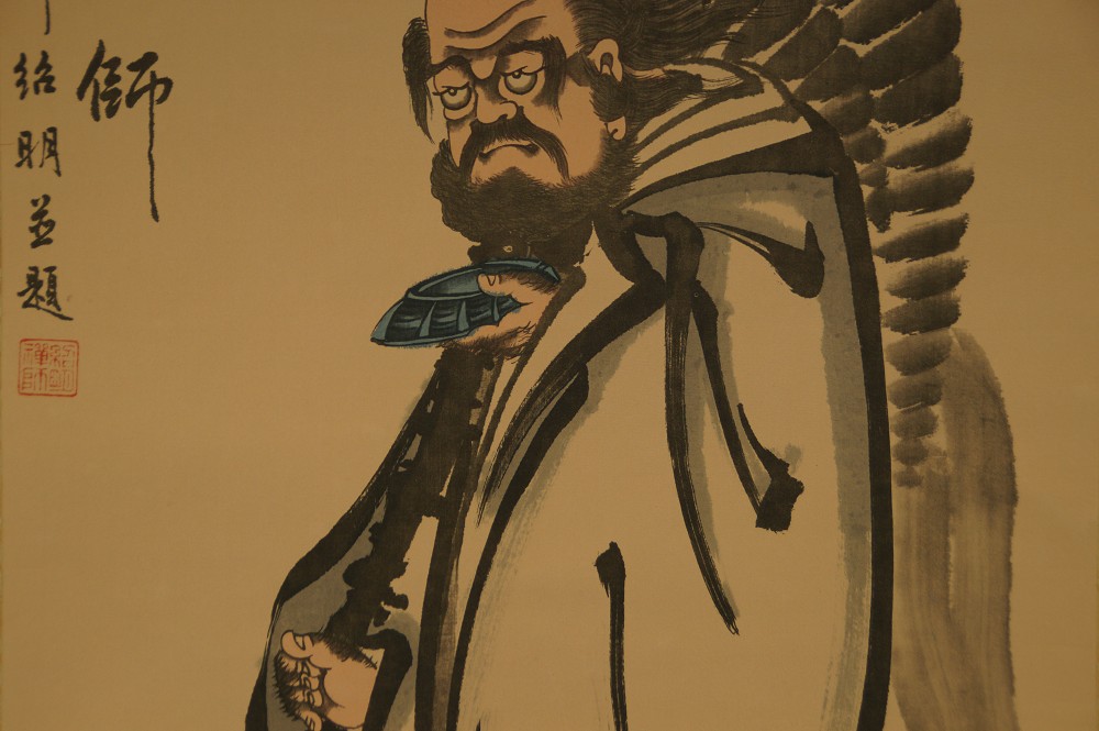 Nahaufnahme des Gesichts von Bodhidharma mit Faecher und Kolophon-Text