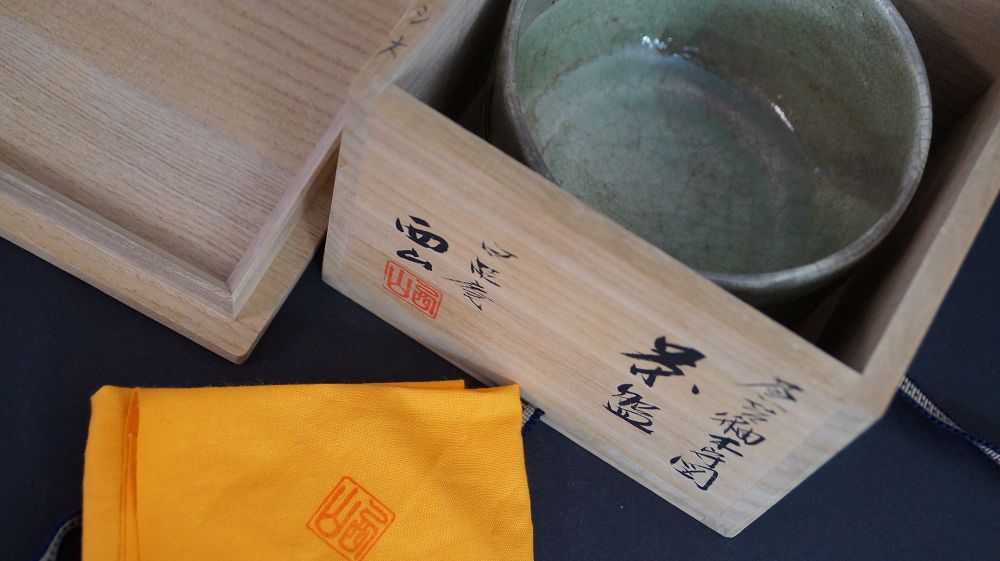 Chawan aus Kyoto-Keramik in der geoeffneten Aufbewahrungsbox neben dem signierten Kastendeckel
