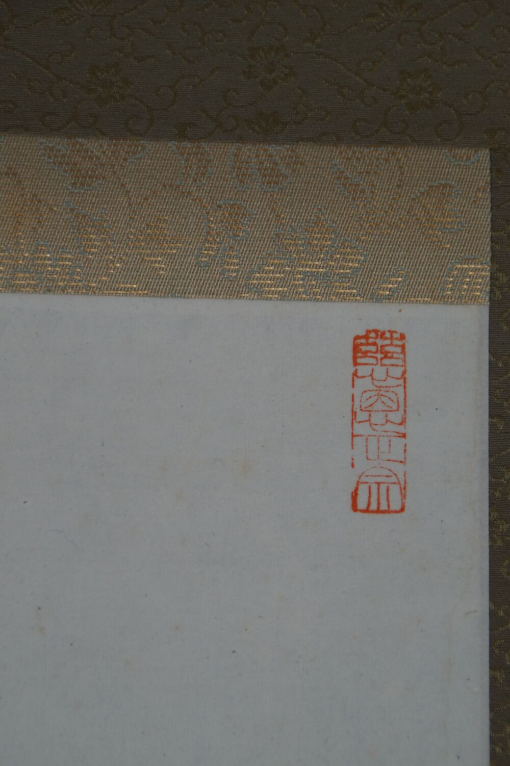 Detailansicht der gemusterten Seidenmontierung mit rotem Siegel am Bildrand des Kakemono Kalligrafie Shoaku Makusa