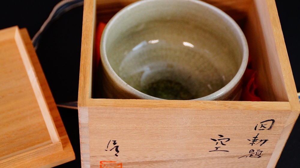 Chawan aus Seto-Keramik in der geoeffneten Aufbewahrungsbox mit roter Seidenauskleidung
