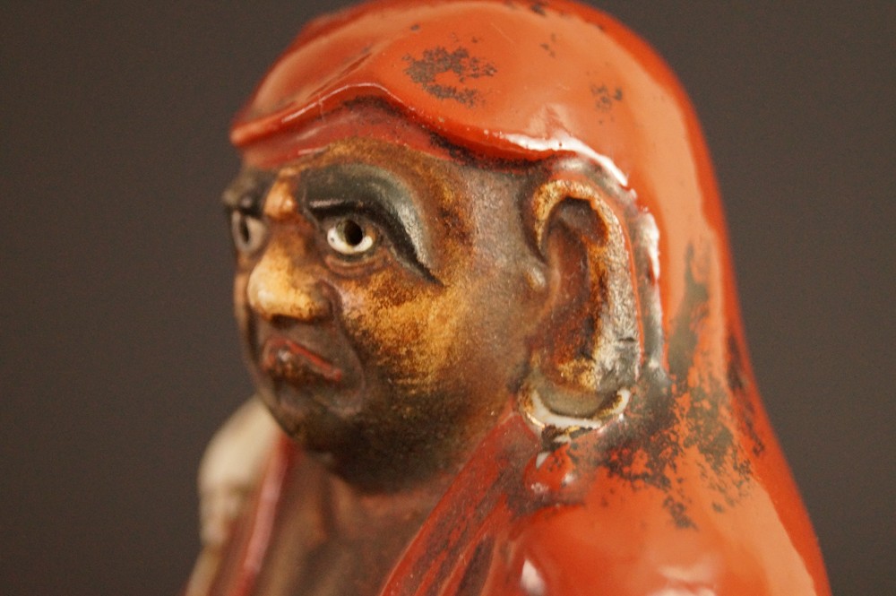 Bodhidharma Daruma Figur aus rotem Kutani-Porzellan Nahaufnahme des Gesichts im Dreiviertelprofil Gesicht Nahaufnahme 2