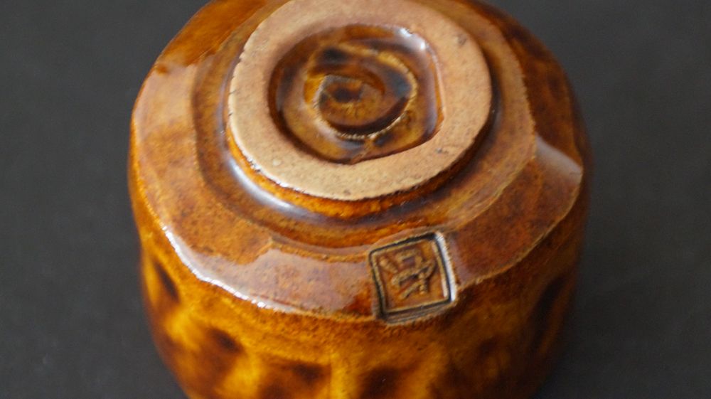 Nahaufnahme des Bodens mit spiralfoermigen Drehrillen und eingestempelter Kuenstlermarke des Guinomi aus Ohi-Keramik von Ohi Cho
