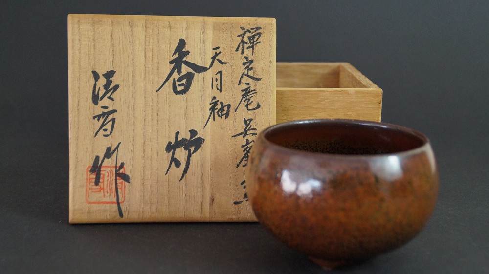 Chawan neben der geoeffneten Aufbewahrungsbox mit Tusche-Beschriftung Tenmoku-Yu Kouro und rotem Siegel