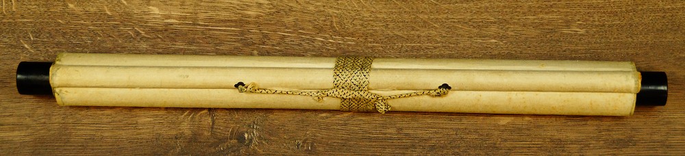 Zusammengerolltes Kakemono mit Kordel und Jikusaki aus Holz auf Holztisch