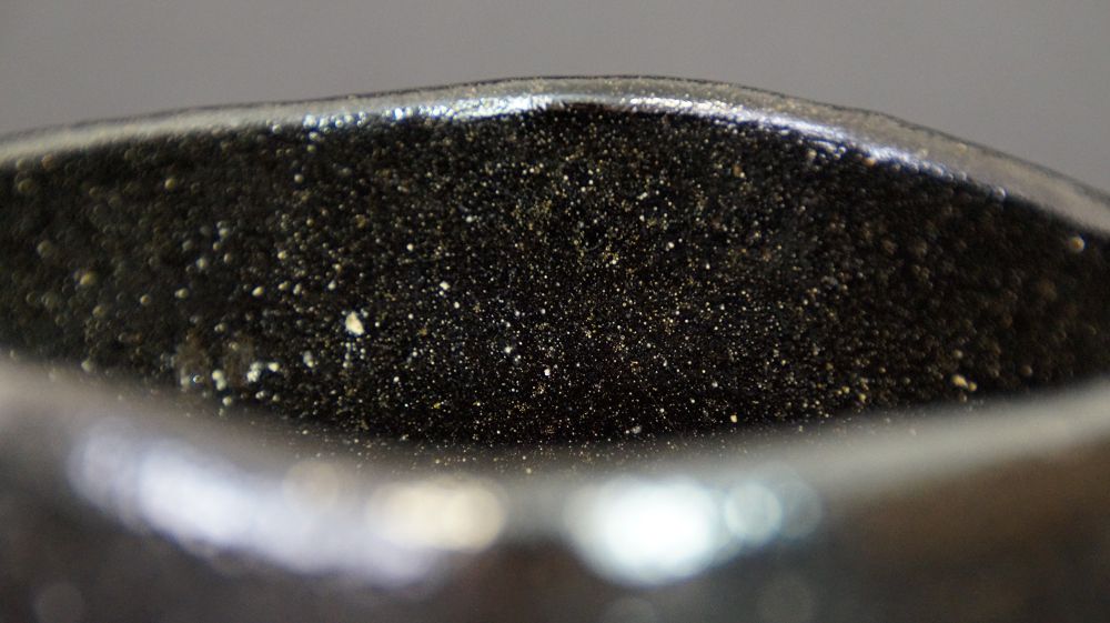 Nahaufnahme des Randes mit schwarzer, goldfarben gesprenkelter Innenglasur der Chawan aus Raku-Keramik