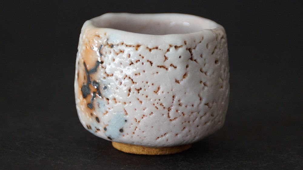 Weitere Seitenansicht des Guinomi aus Shino-Keramik von Takeshi Kato mit dunklen Eisenflecken auf craquelierter Glasur