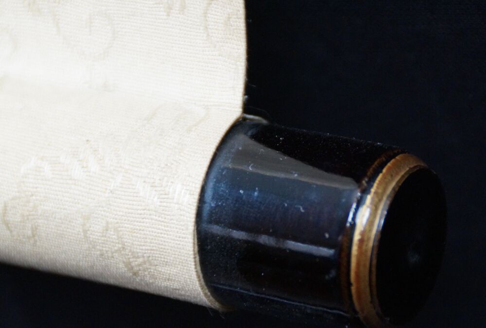 Vue détaillée de l'extrémité du rouleau laquée noire avec soie crème du kakemono Jeune femme devant son armoire à kimono