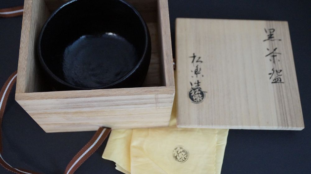 Chawan de cerámica Raku en la caja de conservación abierta junto a la tapa firmada de la caja