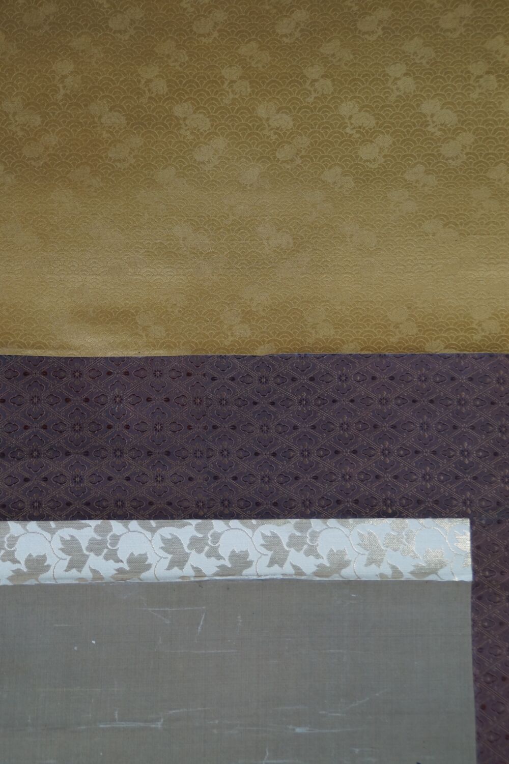 Vue détaillée de la montage en soie dorée et violette avec bordure crème du kakemono Héron dans la splendeur silencieuse des pivoines