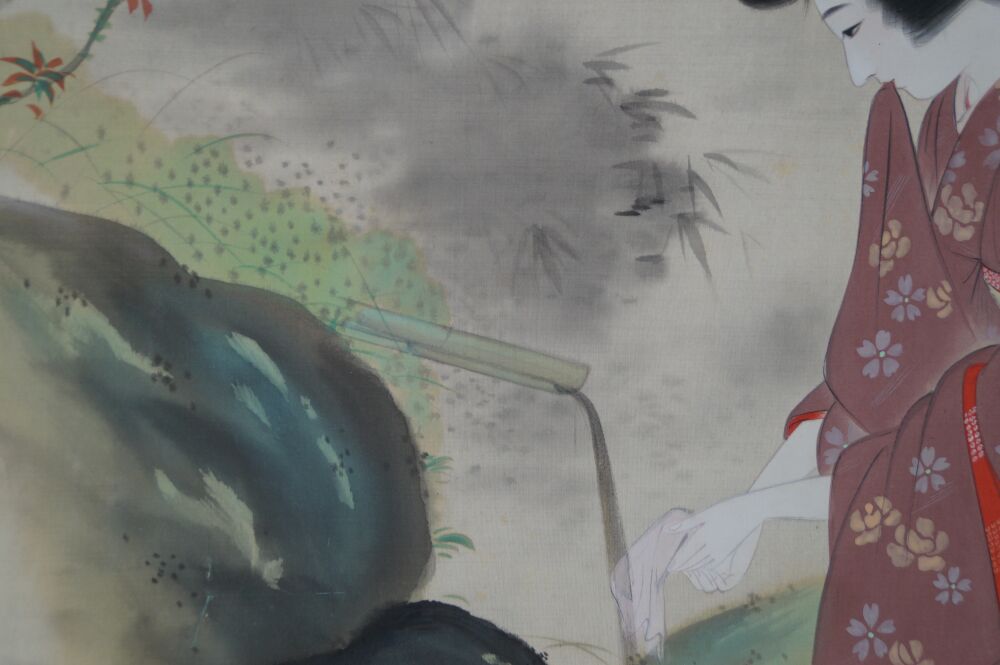 Primo piano di mano e panno bianco presso lo shishi-odoshi di bambù con roccia coperta di muschio e foglie d'acero nel kakemono dama in kimono presso lo stagno del giardino