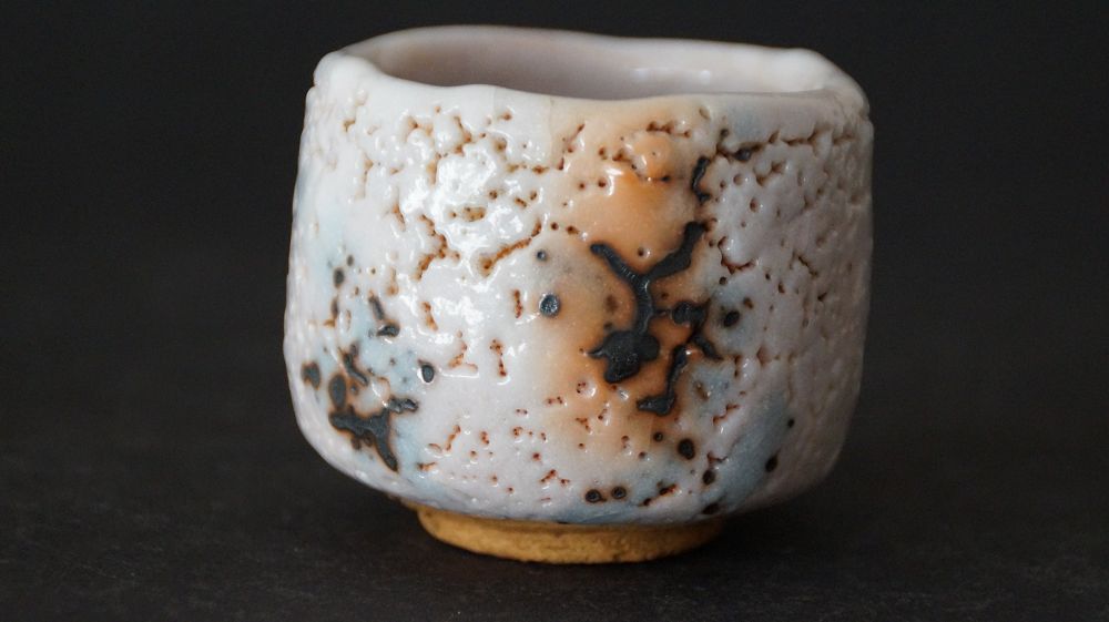 Seitenansicht des Guinomi aus Shino-Keramik von Takeshi Kato mit craquelierter Glasur und dunklen Eisenflecken
