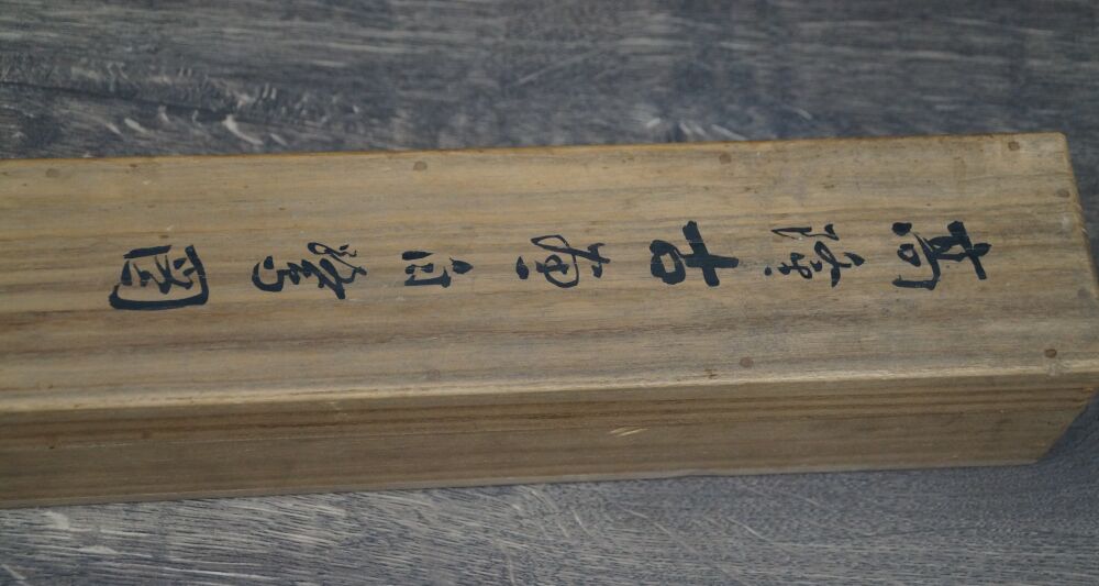 Vue détaillée de l'inscription calligraphiée sur le côté de la boîte de rangement du kakemono Héron dans la splendeur silencieuse des pivoines