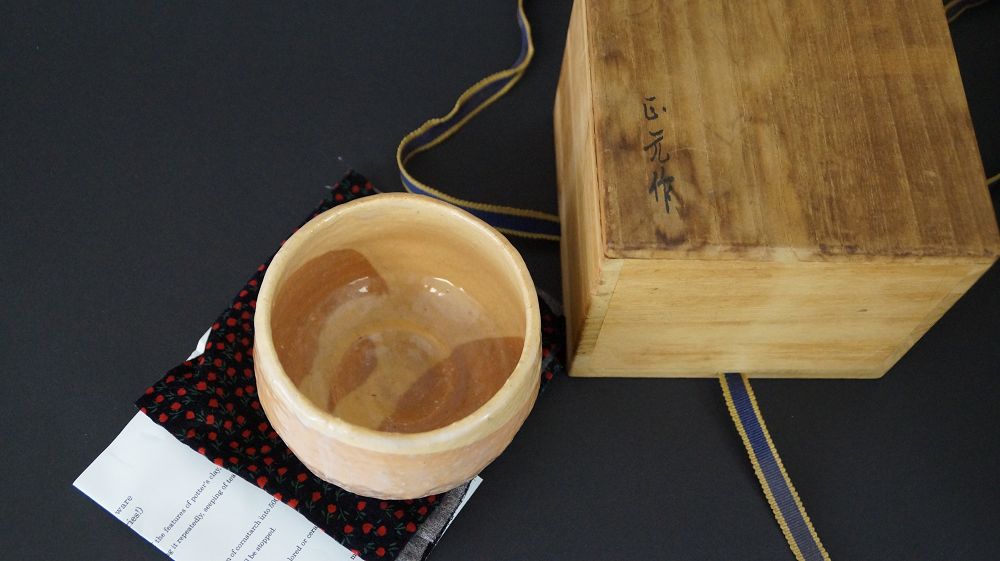 Chawan Teeschale auf gemustertem Tuch neben handschriftlichem Echtheitszertifikat und signiertem Kastendeckel