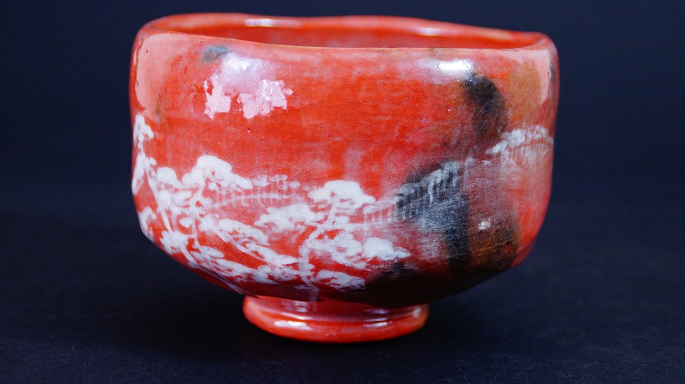 Seitenansicht der Chawan aus Raku-Keramik von Waraku Kawasaki neben der Aufbewahrungsbox mit sichtbarem Kuenstlersiegel