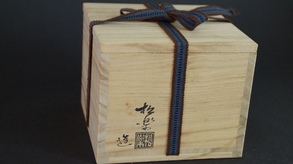 Boîte de conservation fermée du chawan en céramique Raku, attachée avec un ruban brun-bleu