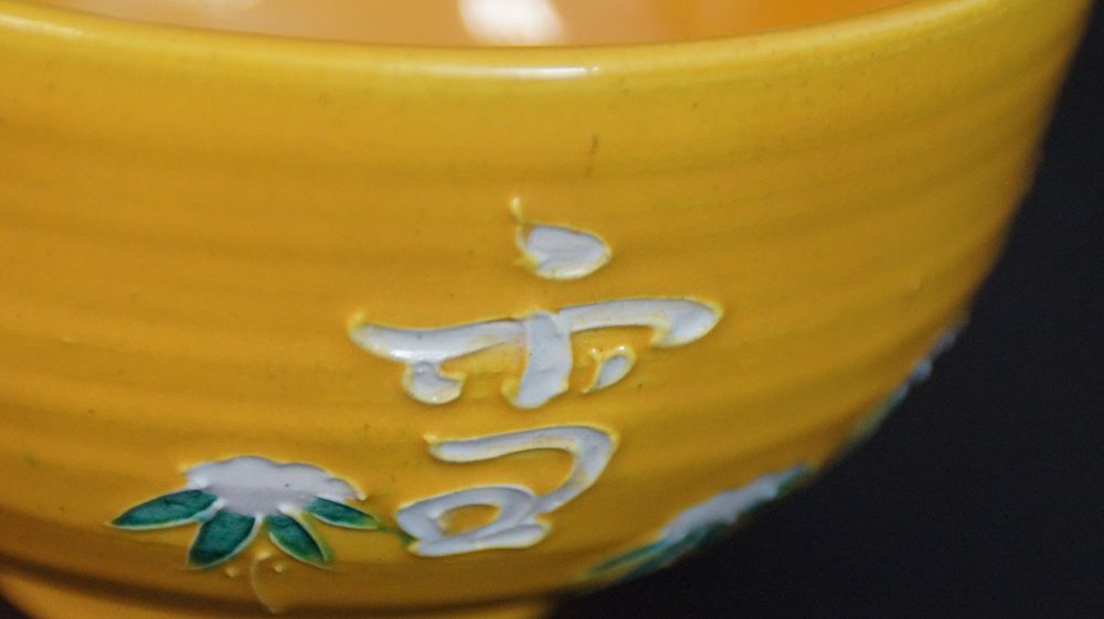 Weitere Nahaufnahme des weiss aufgetragenen Schriftzeichens mit Chrysanthemenmotiv der Chawan aus Kyoto-Keramik