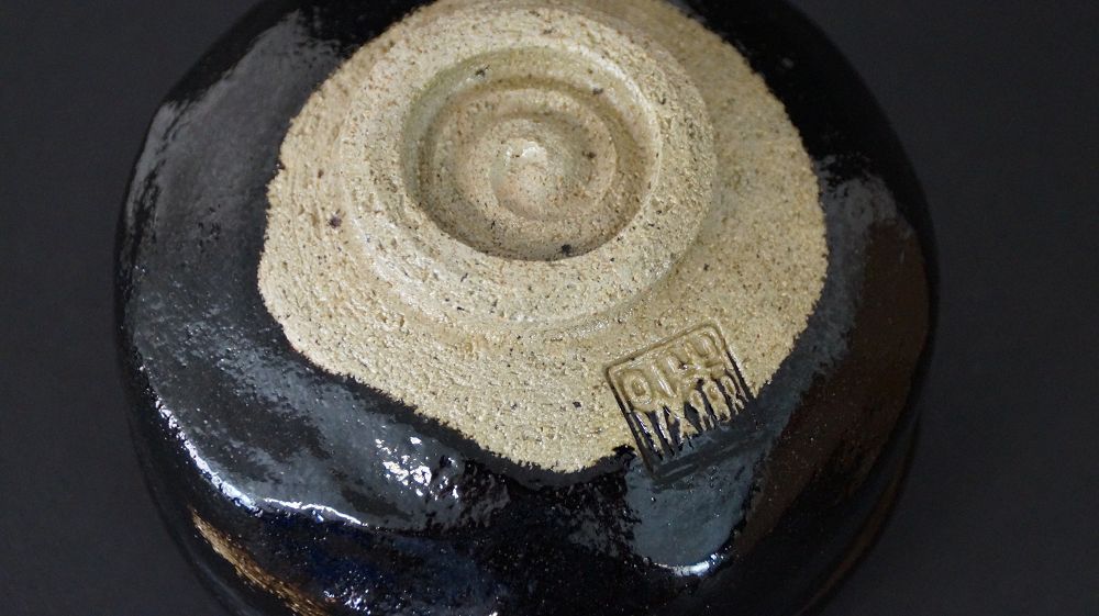 Widok szczegółowy stopki z wyciśniętą pieczęcią artysty czarki do herbaty chawan z ceramiki Raku