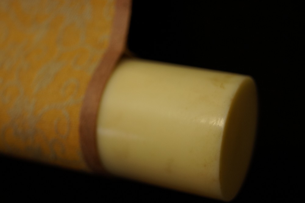 Elfenbeinfarbenes Rollenende mit Brokatstoff Rollendetail