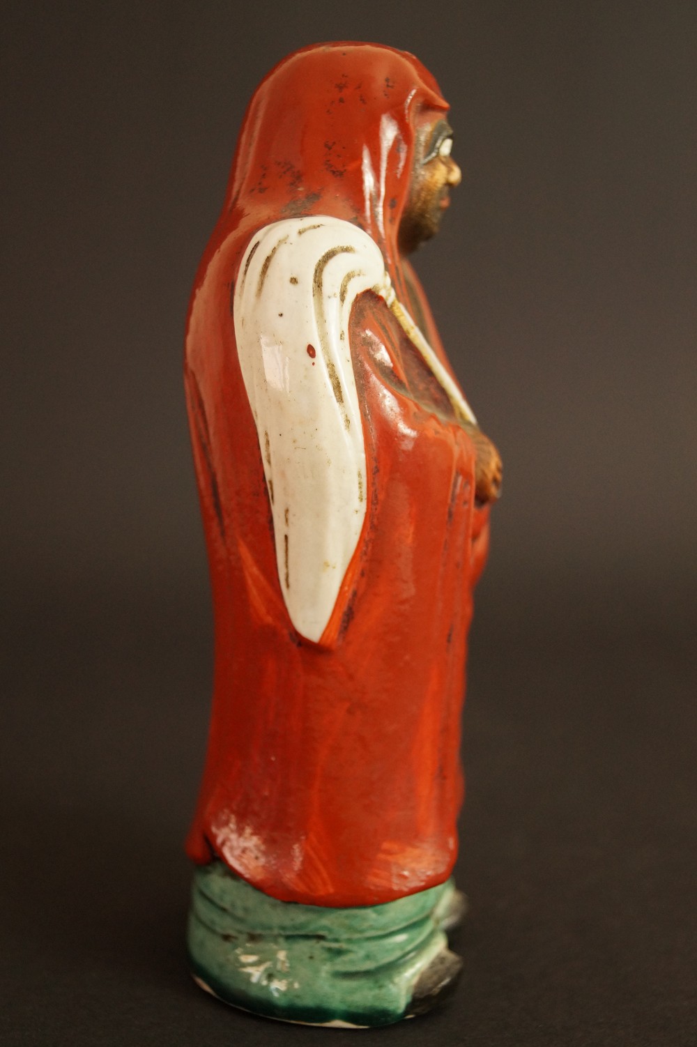 Bodhidharma Daruma Figur aus rotem Kutani-Porzellan Seitenansicht der Figur mit roter Kapuze Seitenansicht