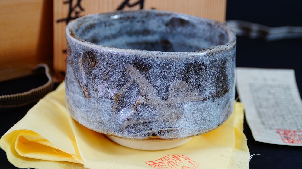 Seitenansicht der Chawan aus Shino-Keramik von Kazufumi Wada neben der Aufbewahrungsbox mit Echtheitszertifikat