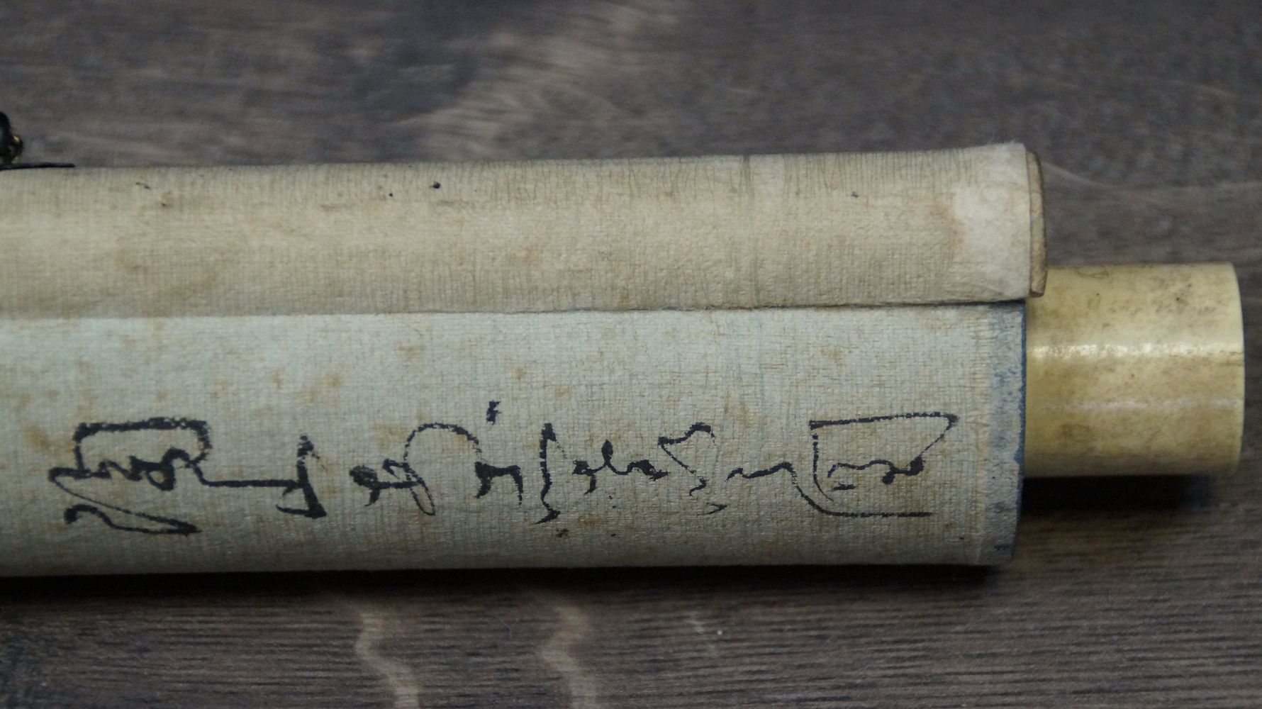 Detailansicht des elfenbeinfarbenen Rollenendes mit handschriftlicher Beschriftung auf der Schutzhuelle des Kakemono Hortensien im Fruehsommerlicht