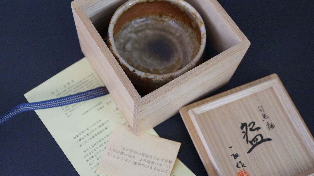 Chawan Teeschale in der geoeffneten Aufbewahrungsbox neben handschriftlichem Echtheitszertifikat und beschriftetem Kastendeckel