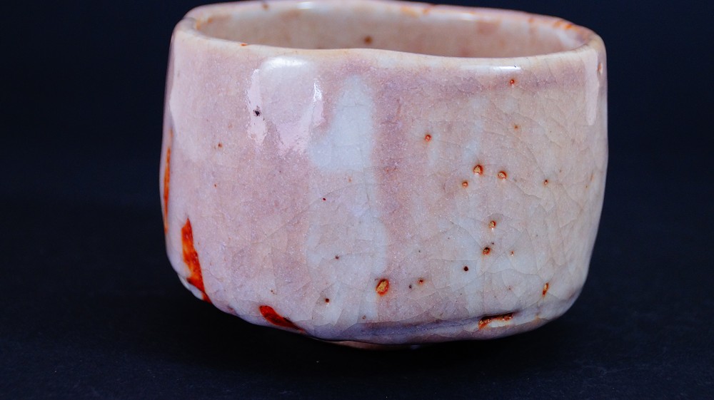 Seitenansicht der Chawan aus Shino-Keramik von Masayoshi Kato mit deutlich sichtbaren roten Feuerspuren