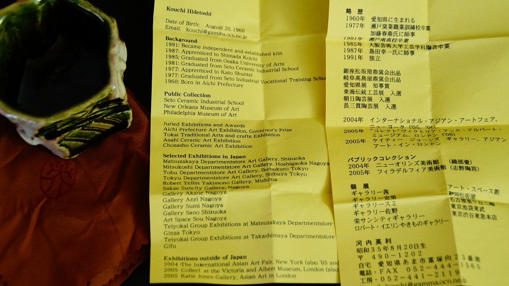 Biografieblatt des Keramikkuenstlers Kouchi Hidetoshi neben dem Guinomi