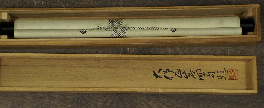 Zusammengerolltes Kakemono in der beschrifteten Aufbewahrungsbox mit Kordel