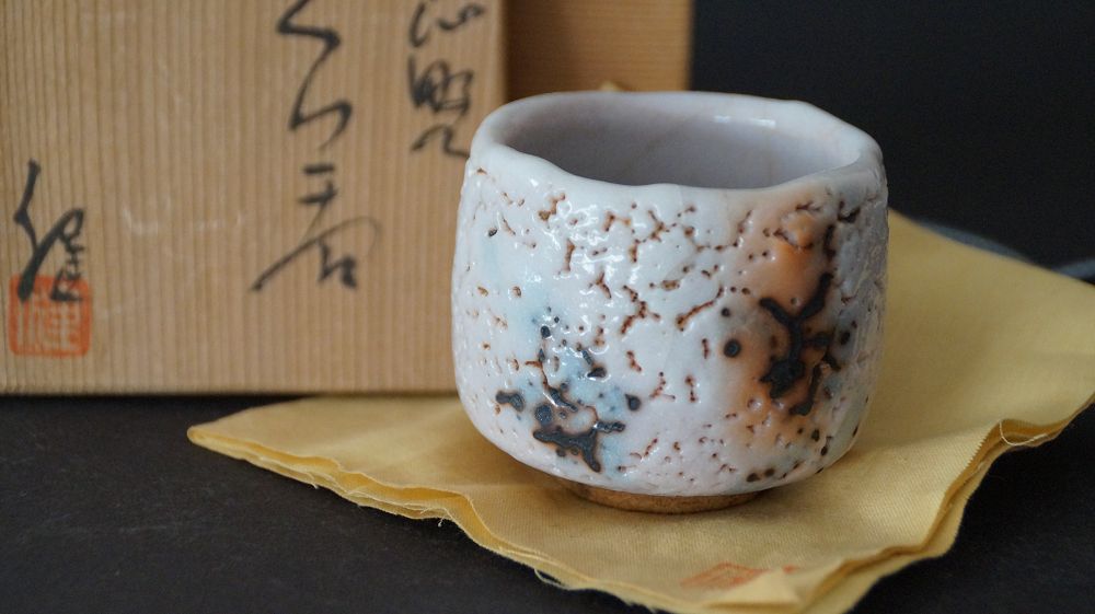 Guinomi aus Shino-Keramik von Takeshi Kato mit der dazugehoerigen beschrifteten Aufbewahrungsbox im Hintergrund