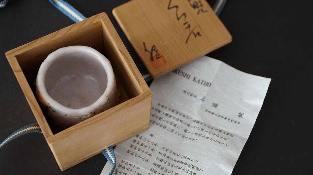 Guinomi aus Shino-Keramik von Takeshi Kato neben der geoeffneten Aufbewahrungsbox mit Echtheitszertifikat
