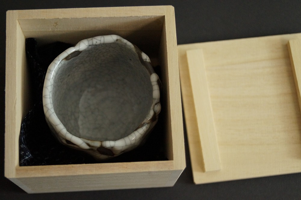 Coppa da sake adagiata nella scatola di legno aperta con fodera interna scura guinomi in scatola di conservazione