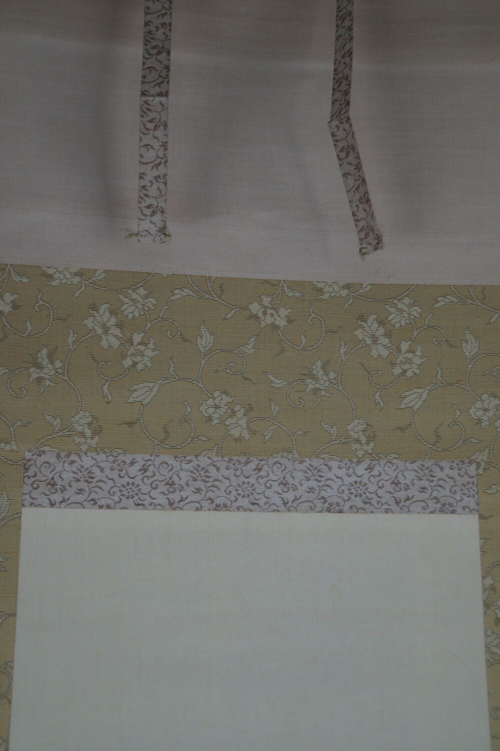 Detailansicht der cremefarbenen Seidenmontierung mit Blumenbrokat und Aufhaengebaendern des Kakemono Hahn und Pflaumenblueten