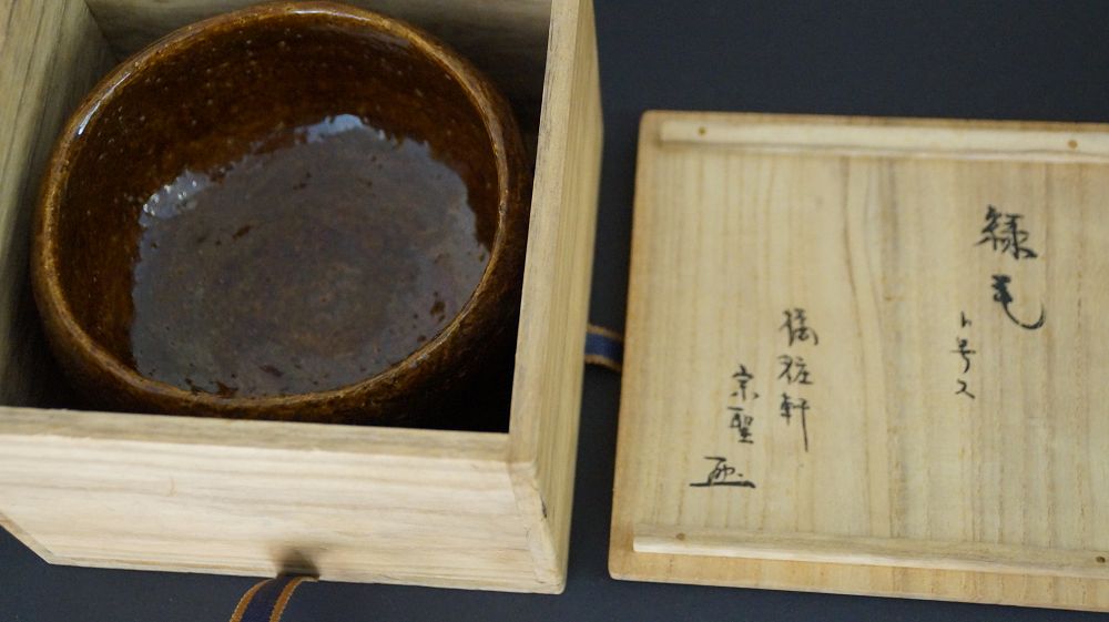 Chawan Teeschale in der geoeffneten Aufbewahrungsbox neben dem beschrifteten Kastendeckel