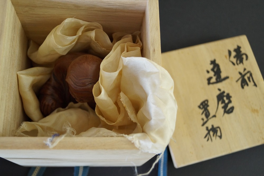 Figura de Bodhidharma en caja de conservación