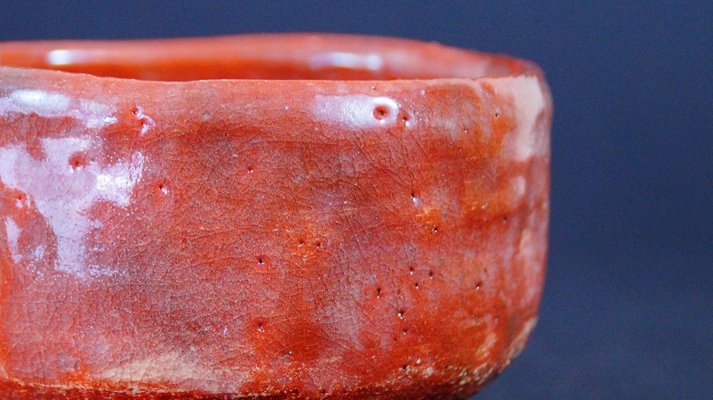 Primer plano del esmalte rojo craquelado del chawan de cerámica Raku por Sairi Hotoku